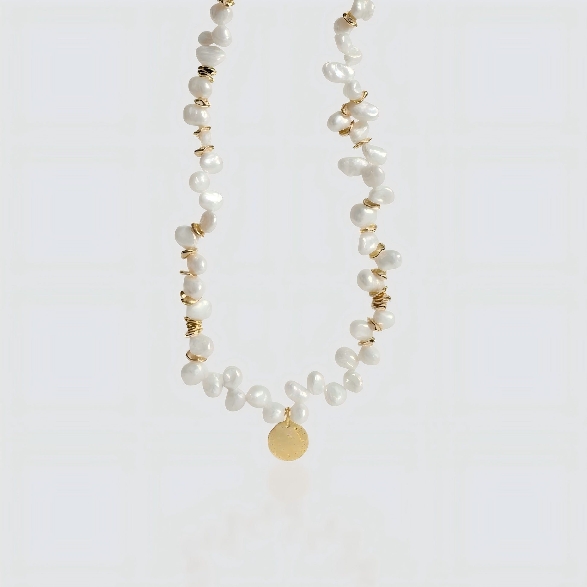 Artisanal Craftsmanship. A crisp look at the interplay between shimmering pearls and the vintage-inspired gold coin.