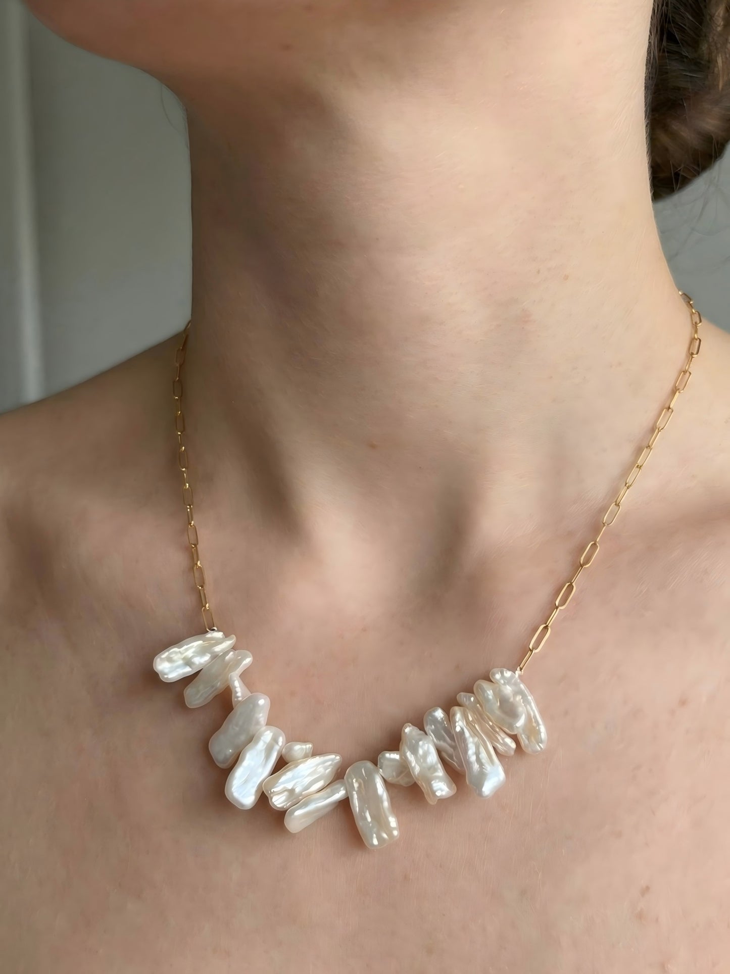 Close-up of a model wearing The Coastal Drift Necklace, showcasing the organic texture of the white baroque pearls and how the piece sits elegantly on the neckline.