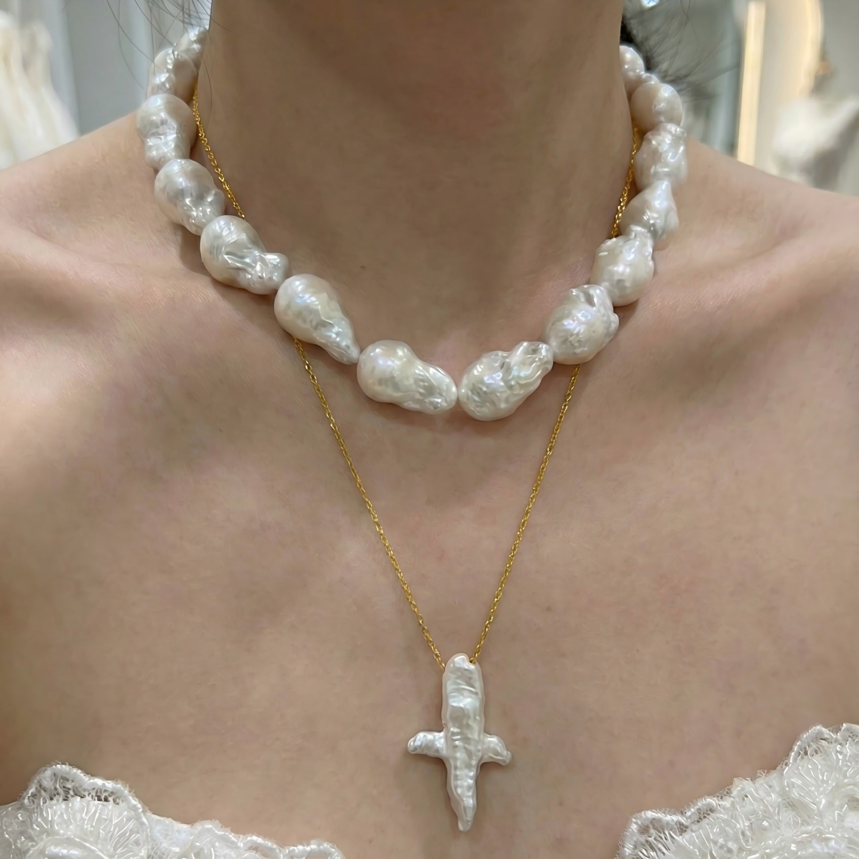 A woman wearing a dainty gold necklace with an abstract star-shaped pearl pendant, styled with a casual chic outfit.