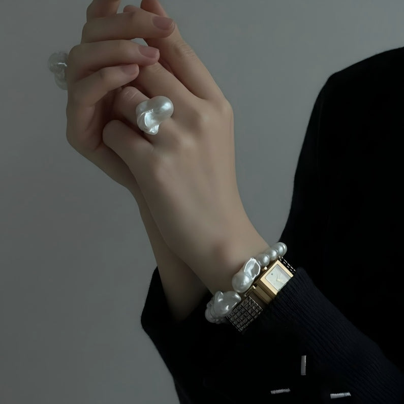 Woman's wrist wearing a chunky baroque pearl bracelet, styled with a neutral outfit to highlight the organic pearl textures and modern asymmetry.