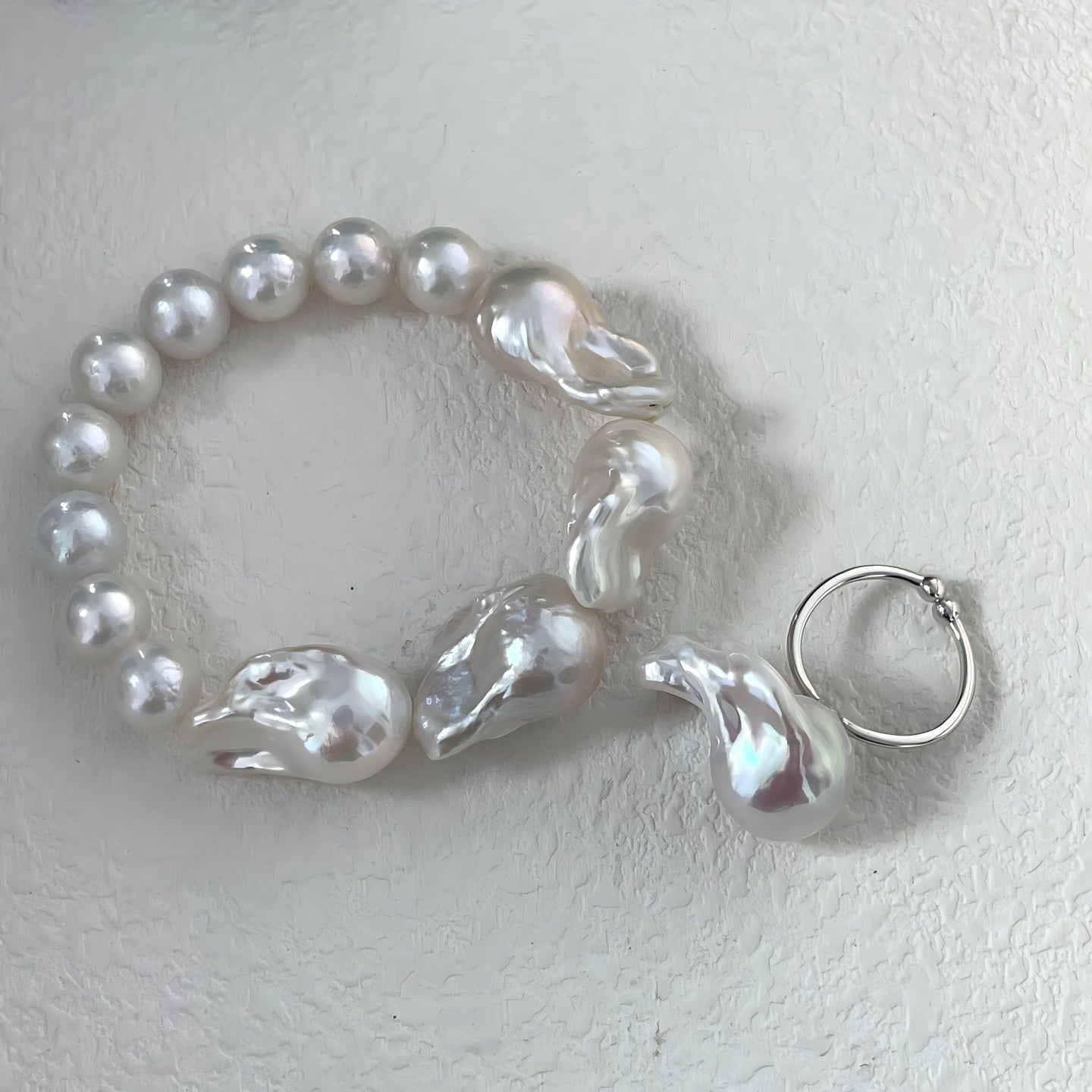 Macro photography detail of large irregular baroque pearls contrasting with smaller round pearls, showing the high luster and natural surface texture.