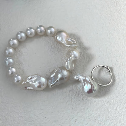 Macro photography detail of large irregular baroque pearls contrasting with smaller round pearls, showing the high luster and natural surface texture.
