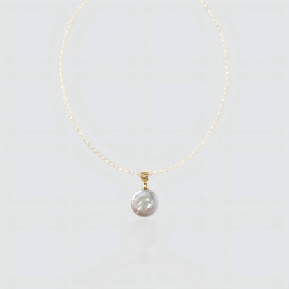 A pristine view of our delicate seed pearl strand featuring a large, lustrous coin pearl pendant with a textured gold bail.