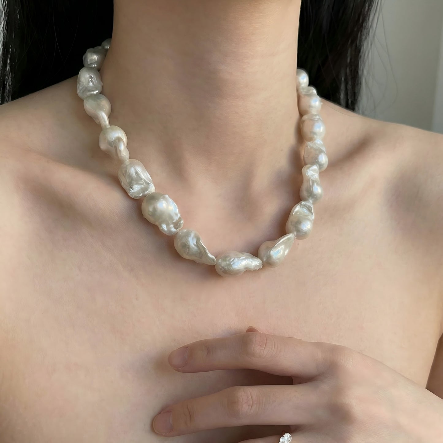 A portrait of modern elegance. The chunky baroque pearls sit beautifully against the collarbone, adding a luminous glow to the skin.
