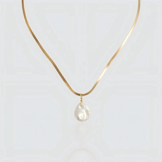 A flat gold snake chain necklace featuring a single white baroque pearl pendant isolated on a light background. The necklace has a sleek, herringbone texture that resembles liquid gold. Minimalist pearl jewelry by Pearltide.