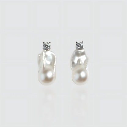 Pair of irregular shaped freshwater baroque pearl earrings with silver posts, isolated on white background.