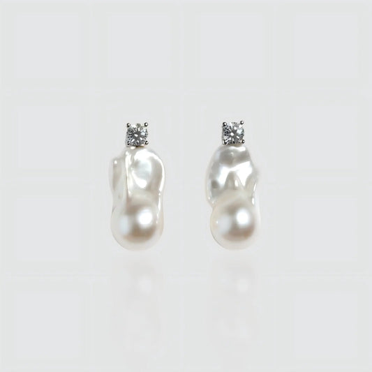 Pair of irregular shaped freshwater baroque pearl earrings with silver posts, isolated on white background.