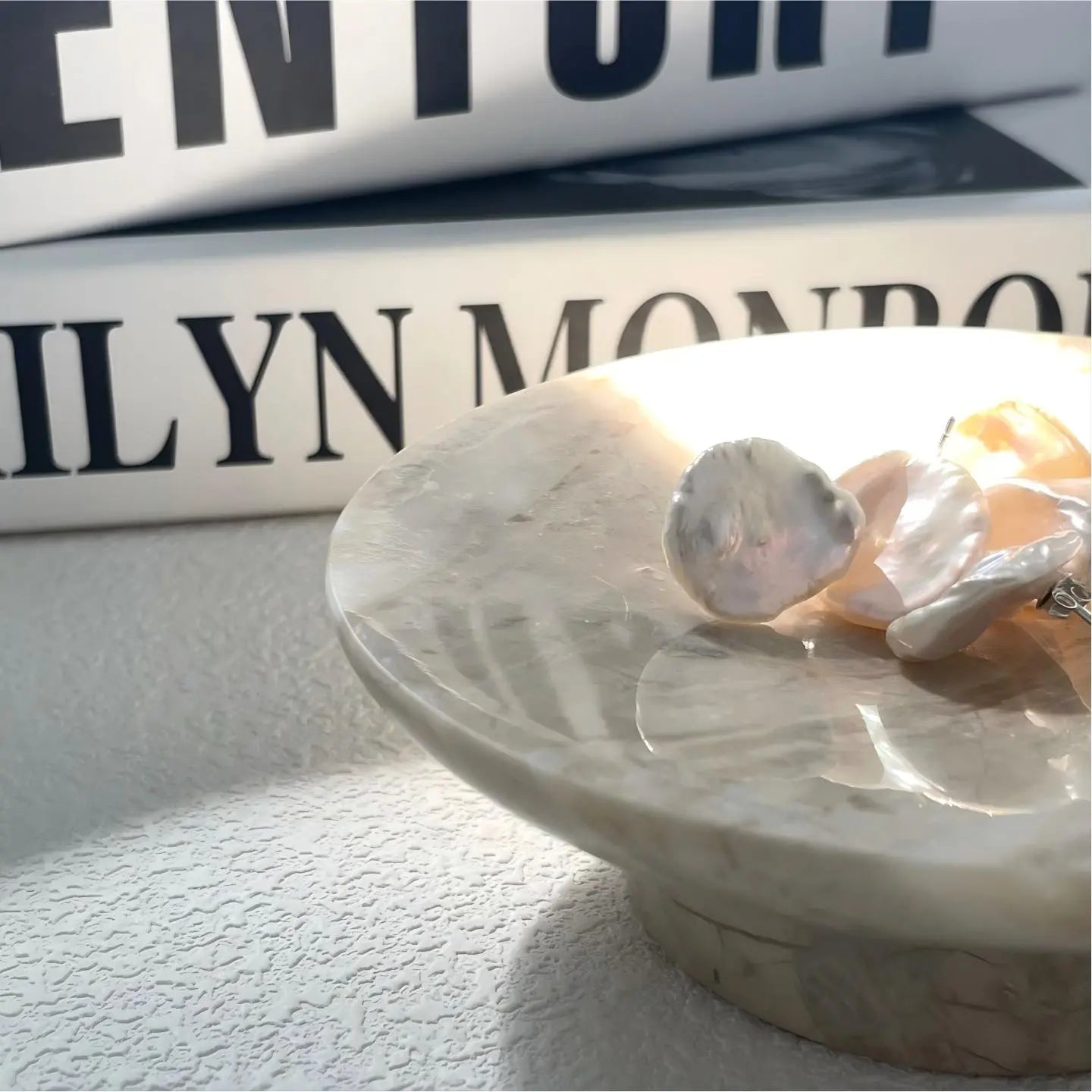 Macro detail shot of a single baroque pearl stud earring. The image highlights the natural, irregular surface texture and the iridescent rainbow overtones of the freshwater pearl, emphasizing its unique, non-spherical coin shape.