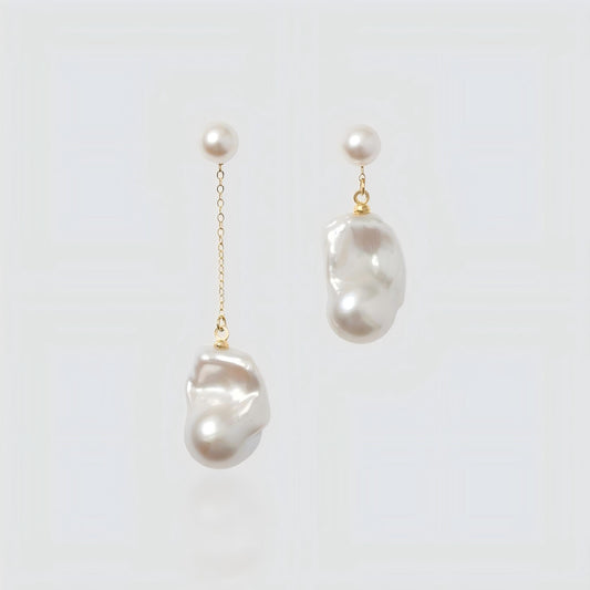 Pair of asymmetrical freshwater pearl earrings on a white background. Left earring features a long gold chain drop, while the right earring is a short drop, both with round pearl studs.