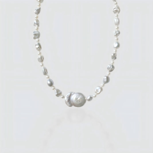 Studio shot of a freshwater baroque pearl necklace featuring a unique "Sun and Moon" center pendant, isolated on a white background.