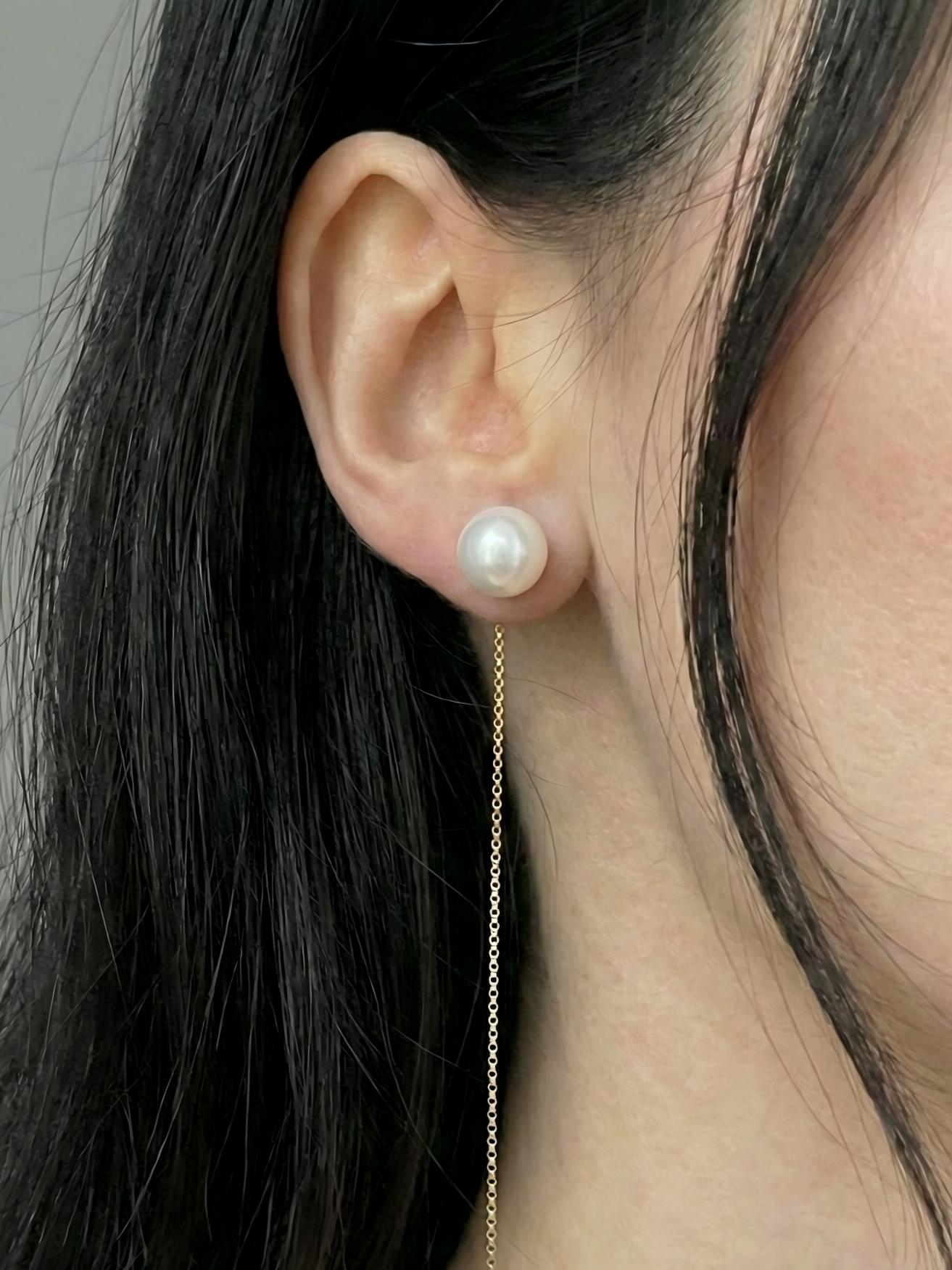 Mujer luciendo unos pendientes de hilo con la perla ajustada al lóbulo y la cadena fina colgando, estética clean look.