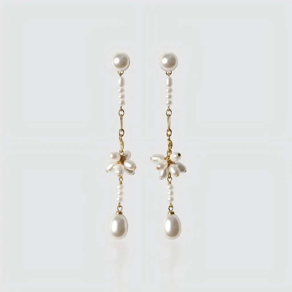 A pair of long gold-plated drop earrings by Pearltide against a plain white background.