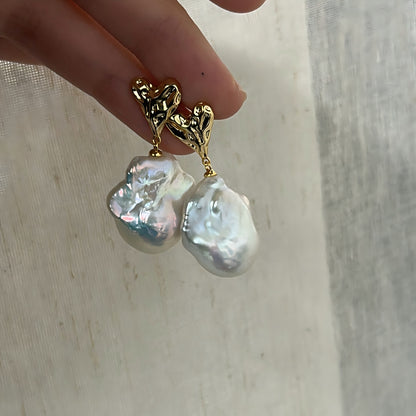 Close-up on the intricate 'crushed gold' texture of the heart stud, paired with the unique natural surface of the baroque pearl.