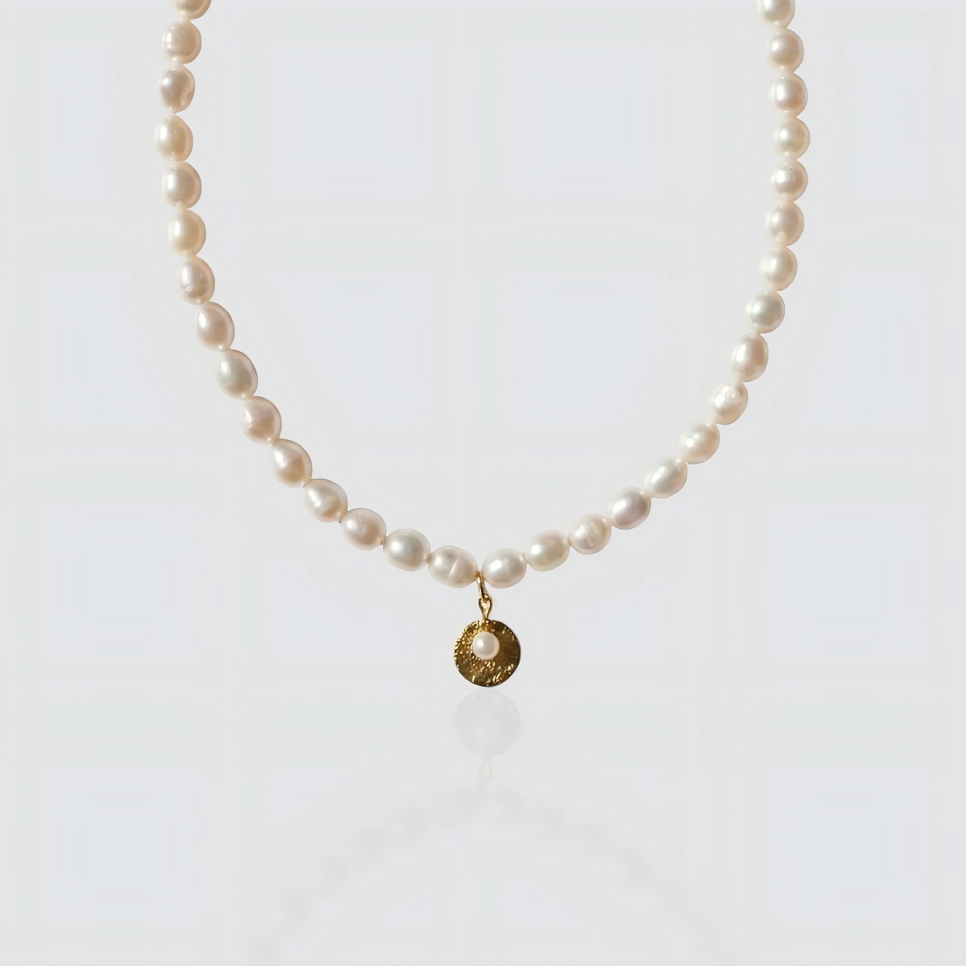Full strand freshwater pearl necklace featuring a textured gold coin pendant with a small pearl center. Vintage-inspired jewelry by Pearltide on white background.