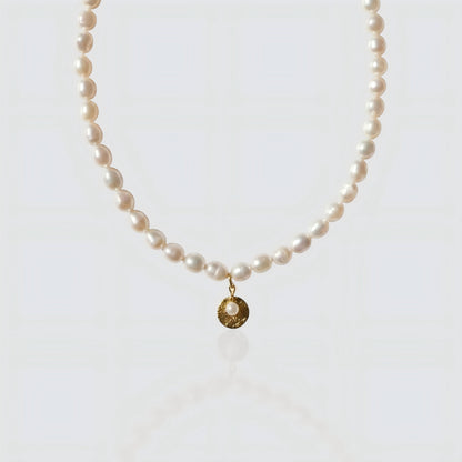 Full strand freshwater pearl necklace featuring a textured gold coin pendant with a small pearl center. Vintage-inspired jewelry by Pearltide on white background.