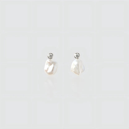 A pair of silver drop earrings featuring small irregular freshwater pearls hanging from round bezel-set cubic zirconia studs.