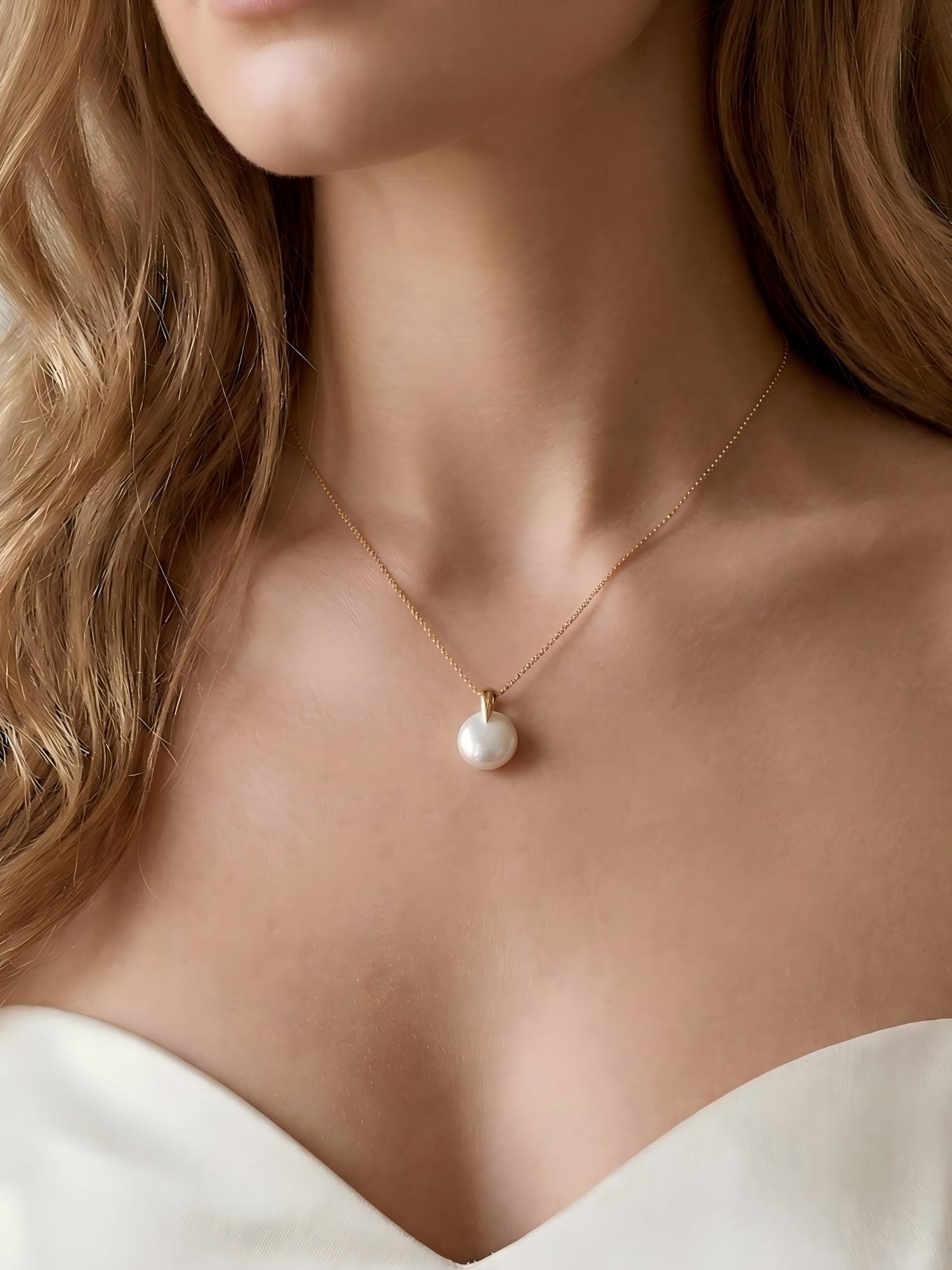 Closeup of the understated Baroque pearl pendant necklace with an off-the-shoulder neckline, perfect for a minimalist bride.