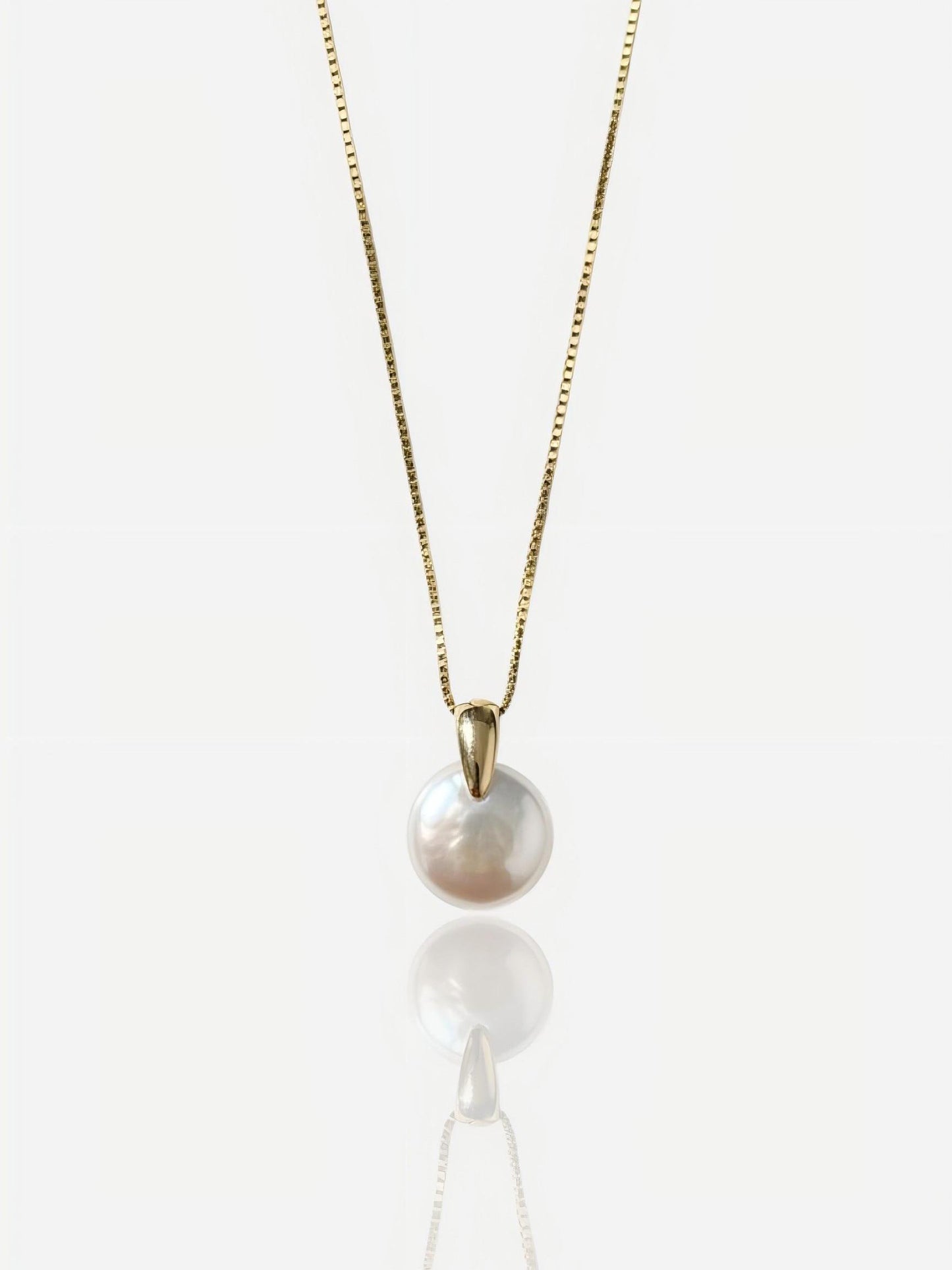 Close-up of Pearltide sleek lunar coin baroque pearl pendant with a modern tapered gold bail on a 14K gold-filled chain, high-luster minimalist bridal jewelry for a clean girl aesthetic.