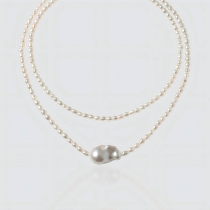 White background shot of a baroque pearl necklace with a unique asymmetrical "Sun and Moon" pendant.