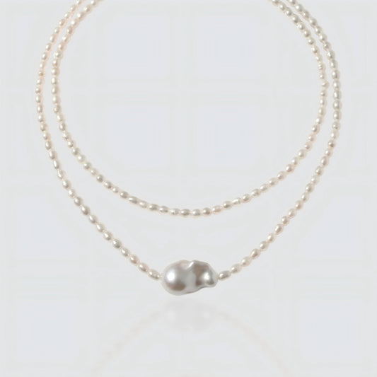 White background shot of a baroque pearl necklace with a unique asymmetrical "Sun and Moon" pendant.