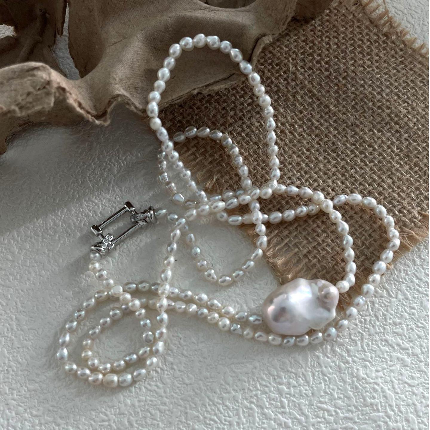 The play between the uniform seed pearls and the organic center pearl is visually stunning.
