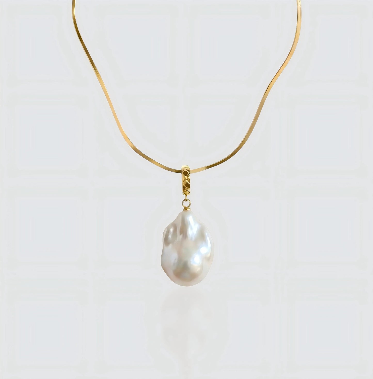 A full view of the Vintage Flat Chain necklace, featuring a sleek gold herringbone chain holding a unique baroque pearl pendant.