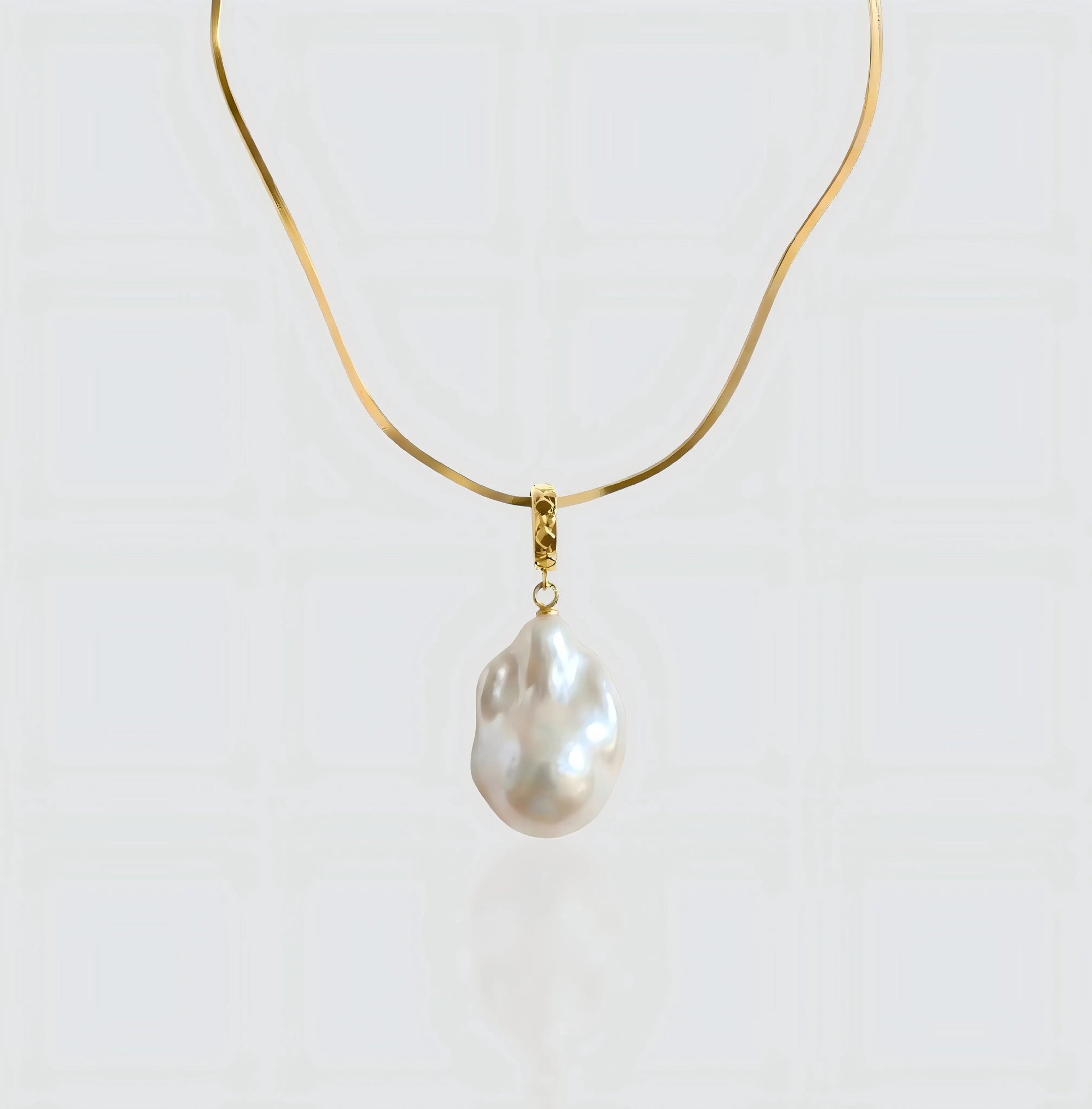 A full view of the Vintage Flat Chain necklace, featuring a sleek gold herringbone chain holding a unique baroque pearl pendant.