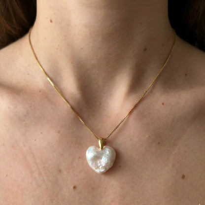 A model wearing a dainty gold necklace with a white heart-shaped pearl pendant, styled for a romantic date night look.

C. 细节图 (Detail Shot - 建议拍摄)