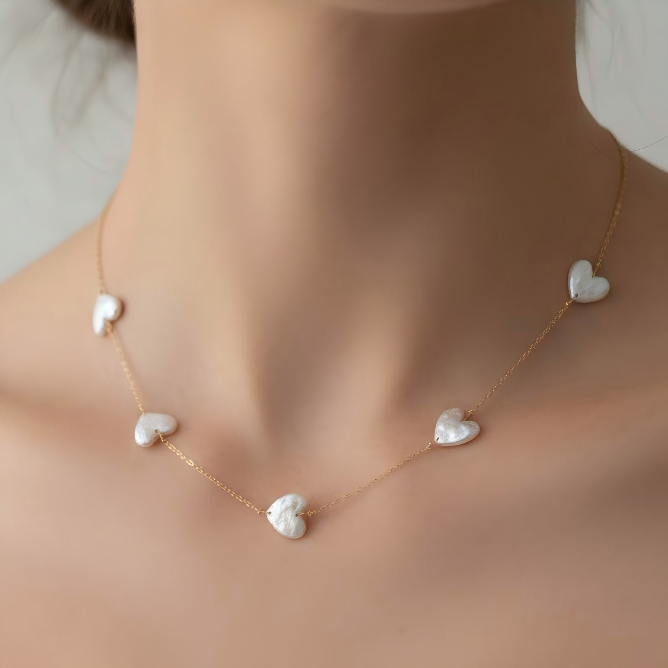 A model wearing the dainty heart pearl station necklace, looking romantic and soft.