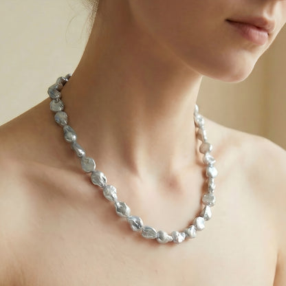 A stylish woman wearing the metallic silver-grey pearl necklace with a black top, highlighting the cool tones of the pearls.