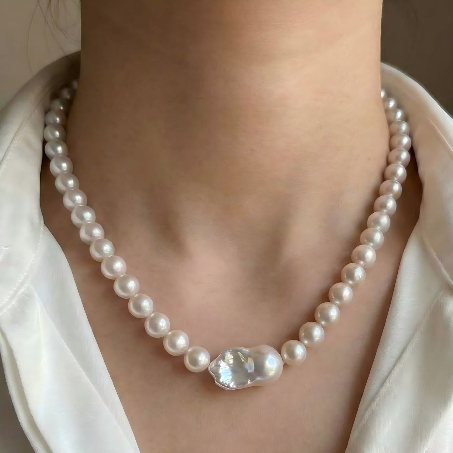 An elegant woman wearing the massive Edison baroque pearl statement necklace with an evening gown, showing its grand scale against the neckline.